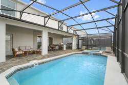 Enjoy a bright private screened pool with a covered patio, outdoor seating, dining table, grill, and lounge chairs. The open sky, modern deck, and relaxing water views create a perfect space for sunny Florida vacation days.
