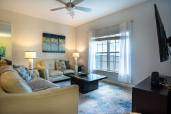 This bright and airy living room boasts a cozy cream leather sofa and a stylish coffee table, all illuminated by soft lamps. Natural light floods in through the large window, creating a warm and inviting atmosphere for guests.