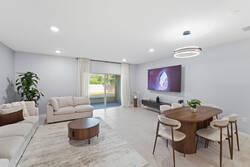Gather in a bright open living and dining area with a cozy sectional sofa, wood dining table, modern lighting, greenery, and a nearby kitchen, creating a comfortable space for your vacation.
