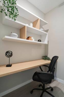 This cozy workspace offers a sleek wooden desk and an ergonomic chair, ideal for productivity or relaxation. Minimalist shelves above showcase stylish decor and greenery, adding a fresh and modern touch to the atmosphere.