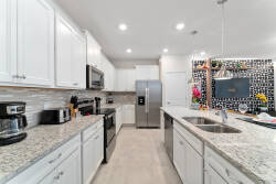 Experience a chic kitchen featuring bright white cabinets and beautiful granite countertops. With modern stainless-steel appliances and a lively accent wall, this inviting space is perfect for your culinary adventures!