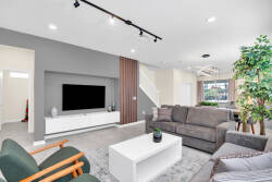 Bathed in natural light, this stylish living room offers a plush sectional sofa and vibrant green chairs for relaxation, complemented by a sleek white coffee table and contemporary media console, creating a chic gathering space.