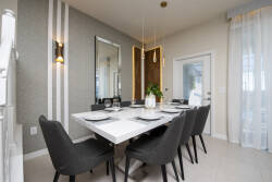 Bright and airy, this dining area features a sleek white table surrounded by plush black chairs, inviting you to savor meals with loved ones. Elegant pendant lights add a warm glow, while large windows frame a refreshing view.