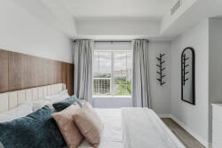 Natural light floods this cozy bedroom, highlighting the textured wooden headboard and soft, plush pillows. The stylish mirror and minimalist decor create a calm atmosphere, perfect for unwinding after a day of exploration.