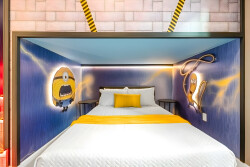Experience a whimsical haven with cheerful Minion-themed murals and a cozy white bed with a vibrant yellow pillow. Soft lighting adds charm, creating the perfect spot to relax after a day of adventure. Enjoy your delightful stay!