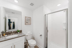 Bright and airy, this contemporary bathroom features sleek white cabinetry and a spacious glass shower. Subtle touches, like the framed artwork and potted plant, add a refreshing charm that enhances your comfort.