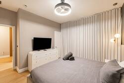 Discover a soothing bedroom adorned in soft gray tones, featuring a plush bed topped with cozy linens. The sleek dresser complements a modern TV, while ambient lighting creates a tranquil atmosphere for restful nights.