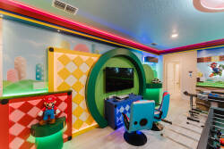 Step into a vibrant gaming haven, where colorful walls adorned with playful designs set the stage for fun. The cozy gaming station features a sleek chair and ample space, ensuring hours of entertainment for guests of all ages.