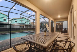 Enjoy our spacious screened patio with a stylish metal dining table and comfy chairs, ideal for al fresco meals. Take in the serene pool view and relax under soft evening lighting that creates a welcoming atmosphere.