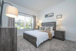 Experience the comfort of this cozy bedroom, filled with natural light that showcases plush carpeting and elegant decor. With a stylish bed frame, soft linens, and inviting lamps, it’s the ideal retreat for your relaxation.