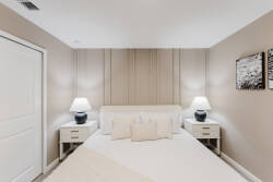 Step into a cozy bedroom adorned with soft beige tones and textured wall accents, creating a tranquil ambiance. The stylish bedside lamps cast a warm glow, while the plush bedding promises restful nights and rejuvenating mornings.