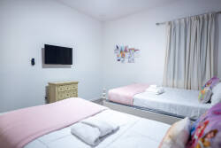 Rest in a dreamy princess-themed bedroom with two cozy beds, elegant white headboards, soft pink accents, and a magical castle mural under a starry sky. Playful pillows and gentle lighting create a sweet space for vacation.