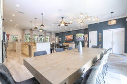 Enjoy meals in this spacious dining area with a beautiful wooden table for eight and cozy black chairs. Large windows let in natural light, enhancing the vibrant blue walls and stylish light fixtures for a welcoming atmosphere.