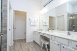 This bright bathroom features a spacious double vanity with ample counter space and stylish lighting. The light wood flooring and white cabinetry create a refreshing, inviting atmosphere for your stay.