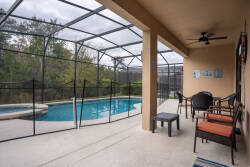 Step outside to this covered terrace, where stylish seating invites you to unwind. Enjoy the tranquil view of the sparkling pool, surrounded by nature, while a gentle breeze flows through the screened enclosure.