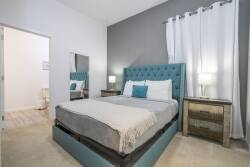 Enjoy restful nights in this stylish bedroom with a plush turquoise tufted headboard and cozy neutral bedding. Soft bedside lamp light accentuates the contemporary decor, while sheer curtains welcome gentle sunlight.