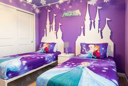 Rest in a charming Frozen themed bedroom with two cozy beds, purple walls, castle-style headboards, snowflake decor, and bright bedding, creating a magical space for kids during vacation.