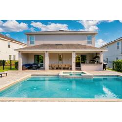 Relax by a private pool with a raised spa, covered patio, outdoor kitchen, dining area, and comfortable seating, creating the perfect backyard space for sunny Florida days.