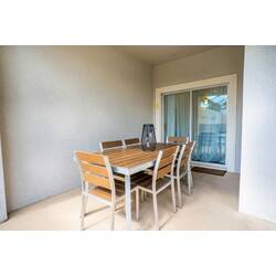 Step outside to a cozy dining area featuring a sleek wooden table and modern chairs, perfect for al fresco meals. The sliding glass doors let in natural light, seamlessly blending indoor comfort with outdoor charm.