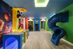 Bright and colorful, this playful entertainment room features a vibrant mural and a fun slide, perfect for kids to enjoy. The playful design and energetic colors create a dynamic atmosphere for family fun and relaxation.