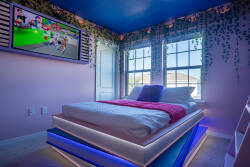 This vibrant bedroom offers a plush bed with colorful accents and stylish LED lighting for a lively atmosphere. Large windows bring in natural light, while playful decor and a mounted TV enhance your evening entertainment.