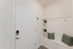 Enter a warm space with a bright white door and cozy seating, ideal for unwinding after your adventures. The light walls and soft green cushions create a fresh, inviting atmosphere that enhances your stay.
