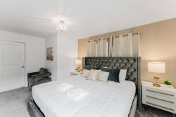 This beautifully designed bedroom boasts a plush tufted headboard and soft, neutral tones for a calming ambiance. Elegant bedside lamps provide warm lighting, creating an ideal space for relaxation after your day's adventures.