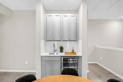 Enjoy a beautifully designed kitchenette with elegant gray cabinetry and a chic wine cooler, perfect for unwinding after your adventures. The warm wooden dining table invites you to gather in a cozy and welcoming atmosphere.