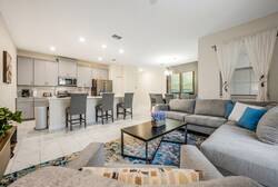 Experience a beautifully designed living space featuring a spacious layout with a large sectional sofa and sleek coffee table. The modern kitchen, with stylish bar seating, is ideal for casual gatherings, all enhanced by warm.