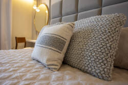 Enjoy peaceful nights in this beautifully styled bedroom with a plush quilt and textured pillows that beckon relaxation. The soft lighting sets a warm ambiance, and the chic accent chair adds a sophisticated touch to your stay.