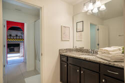 Experience a stylish bathroom featuring rich dark cabinetry paired with sleek granite countertops, offering a touch of modern comfort. The warm lighting illuminates the space, creating a welcoming atmosphere for your stay.