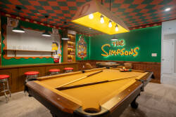 Welcome to a vibrant haven where green walls and a unique checkered ceiling create a fun atmosphere. Enjoy friendly competition at our classic pool table, complemented by retro bar stools that add nostalgia to your game nights.