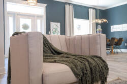 Step into a cozy living area featuring a plush, light-colored sofa draped with a soft green throw, inviting you to relax. The rich teal walls and natural light create a vibrant yet calm atmosphere, perfect for unwinding together.