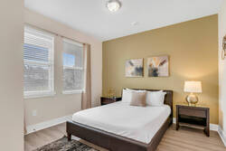 Rest in a cozy bedroom with a comfortable bed, warm accent wall, soft bedding, bedside lamps, abstract wall art, natural light, and neutral decor for a relaxing stay.
