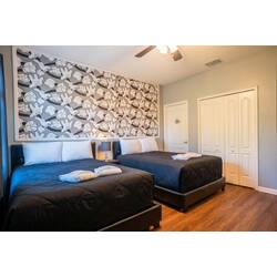 This cozy room features two spacious beds with rich black linens and a stylish patterned accent wall. The warm wood flooring and soft lighting create a perfect ambiance for relaxing after your day of adventure.