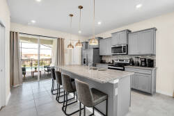 Step into this bright kitchen with sleek gray cabinetry and a beautiful granite island, ideal for casual dining. Large windows fill the space with natural light, and elegant pendant lights elevate your cooking experience.