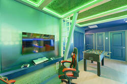 Enjoy a soccer themed gaming nook with framed jerseys, stadium wall art, arcade controls, LED lighting, soccer ball decor, and a colorful seat, creating a fun space for vacation entertainment.