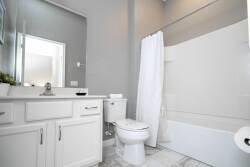 Step into a bright, airy bathroom featuring sleek white cabinetry and soft gray walls that create a calming atmosphere. The clean, modern tub invites relaxation, while ample natural light streams in, enhancing the pristine design.