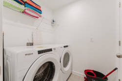 This bright laundry room is designed for your convenience, featuring modern appliances against clean white walls. With colorful, neatly arranged storage, it adds a cheerful touch that makes chores feel more manageable.