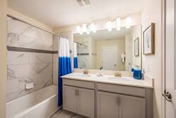 Bright and welcoming, this bathroom features a spacious double vanity with sleek gray cabinetry and polished counters. The modern tile design and vibrant blue accents create a fresh ambiance, perfect for starting your day right.