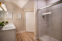 Step into a thoughtfully designed bathroom featuring sleek double sinks and a spacious, glass-enclosed shower. The warm wooden flooring complements soft, neutral wall tones, creating a refreshing atmosphere for your rejuvenation.