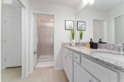Experience a bright bathroom with sleek light cabinetry and a luxurious granite countertop. Framed botanical prints create a tranquil atmosphere, while the spacious shower provides a refreshing retreat. Enjoy your serene oasis!