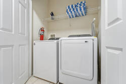 Experience the convenience of an in-unit laundry area, featuring sleek white appliances and ample shelving for your essentials. The clean, bright space ensures you can easily keep your clothes fresh during your stay.