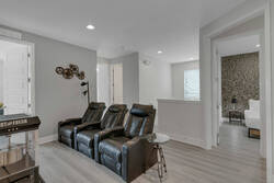 Relax in a cozy cinema lounge with leather recliners, a popcorn machine, movie-themed decor, soft lighting, and easy access to nearby bedrooms for comfortable family movie nights.