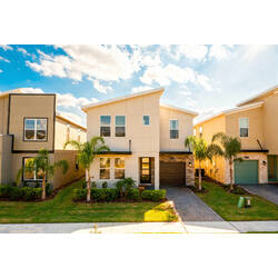 Arrive at a beautiful modern vacation home with a spacious driveway, private garage, palm trees, stone accents, fresh landscaping, and a bright exterior under the Florida sun.