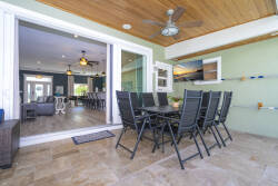 Enjoy our spacious outdoor dining area, where a stylish table meets rich wood paneling and a refreshing breeze from the ceiling fan. With sliding glass doors, indoor and outdoor living blend seamlessly, ideal for entertaining.