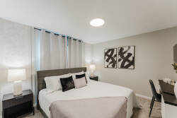This inviting bedroom offers a cozy queen bed with plush pillows and a soft throw, enhanced by stylish artwork. Enjoy a soothing ambiance as soft natural light filters through the elegant curtains, making your stay truly relaxing.