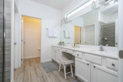Welcome to this beautifully designed bathroom with a spacious double vanity, elegant white cabinetry, and abundant mirror space.