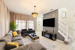 Experience a stylish living area featuring cozy gray seating and elegant black furniture, all illuminated by a beautiful chandelier.