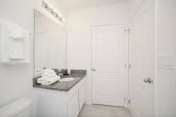Enjoy a bright bathroom with sleek granite countertops and clean white cabinetry. Plush towels offer comfort while the ample lighting creates an inviting atmosphere for a refreshing start to your day.